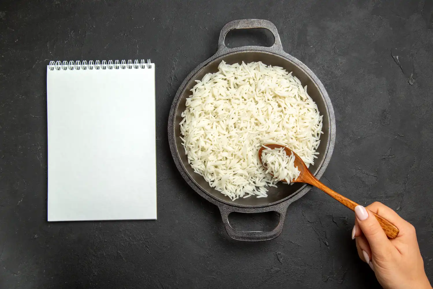 A hand stirring parboiled rice in a pot as part of the process for how to make Iranian tahdig.