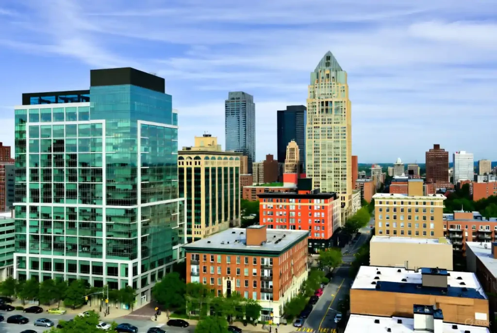 Aerial view of Jersey City with modern glass skyscrapers and historic brick buildings under a blue sky.