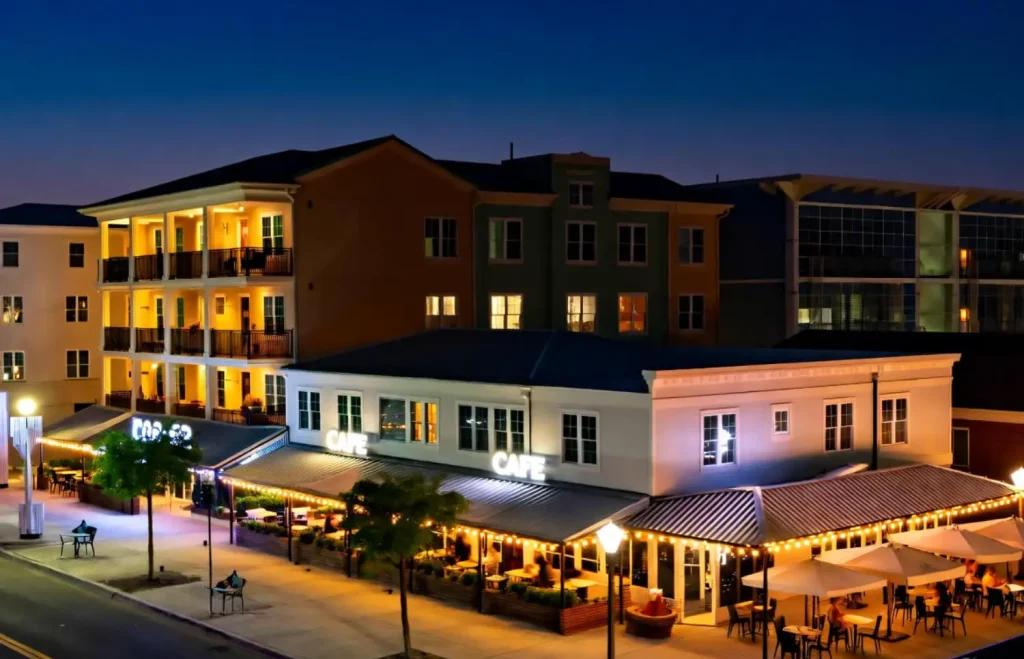 A lively Virginia Beach café with outdoor seating and string lights at night.