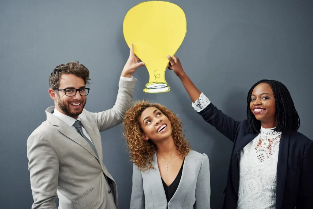 How to identify a business idea: diverse business team holding a yellow paper lightbulb.