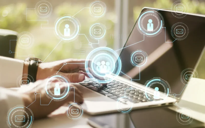 Hands typing on a laptop with digital connection icons.