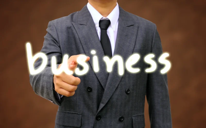 A businessman in a suit pointing at the word "business," symbolizing the Iranian Business Community in Dallas.