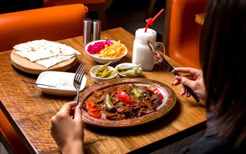 A flavorful Persian meal with kebabs, fresh vegetables, yogurt, and bread at a restaurant.