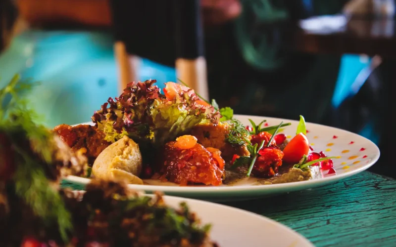 A beautifully plated Persian dish with fresh greens, tomato garnish, and traditional flavors on a white plate.