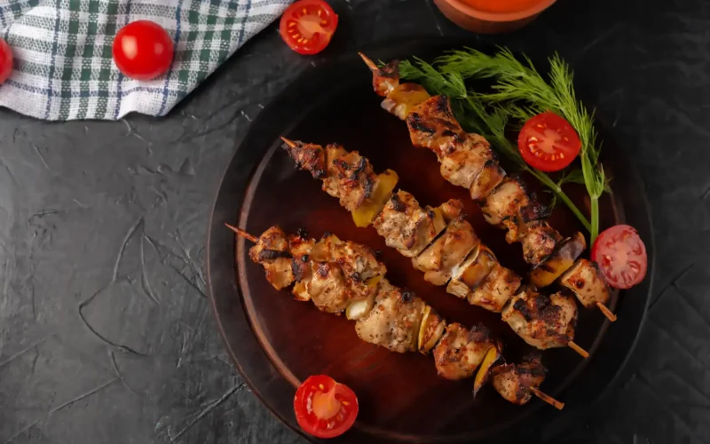 Grilled chicken kabobs served with fresh herbs and cherry tomatoes at Saloona, part of the Iranian Business Community in Dallas.